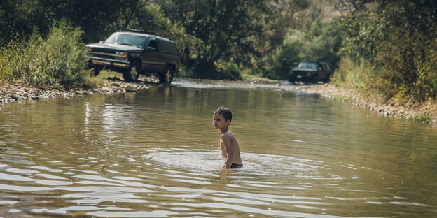 Ein Junge badet im Fluss.