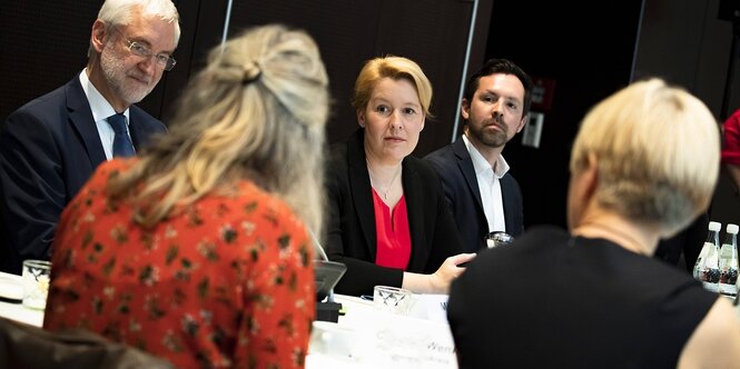 Franziska GIffey unterhält sich an einem Besprechungstisch mit einer Frau, andere hören zu