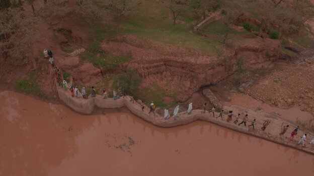 Viele Menschen laufen über einen Staudamm