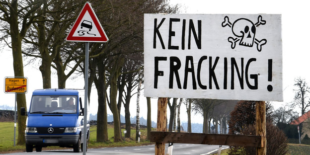 Eine Straße in Niedersachsen. Im Vordergrund ist ein Schild, auf dem „Kein Fracking“ steht. Neben dem Schriftzug ist ein Totenkopf abgebildet.
