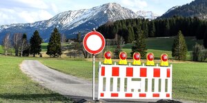 Ein rot-weißes Absperrgitter an einem Deutsch-Österreichischen Grenzübergang mit imposanter Berglandschaft im Hintergrund