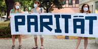 Frauen halten Banner mit der Aufschrift "Parität" hoch