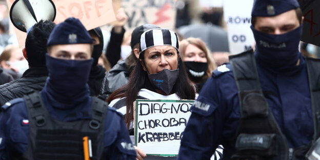 Zwei vermummte Polizisten gehen Demonstrantinnen gegen das strikte Abtreibungsverbot in Polen voraus