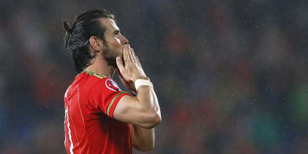 Gareth Bale steht im Trikot von Wales im Regen