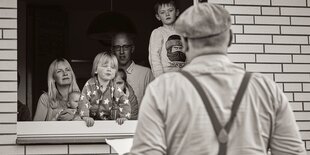 Ein Mann steht vor einem Fenster, aus dem Kinder schauen.