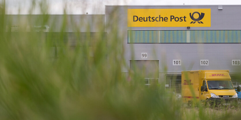 Gras im Vordergrund verdeckt ein DHL-Paketzentrum