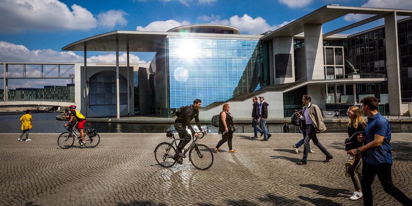 Passanten laufen entlang der Spree in Berlin vor einem Regierungsgebäude, dem Marie-Elisabeth-Lüders Haus