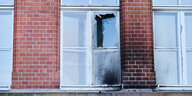 Ein zerbrochenes und verrußtes Fenster des Robert Koch Instituts in Berlin nach dem Brandanschlag