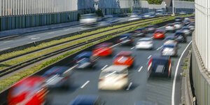 Viele Autos fahren im Berufsverkehr auf der Autobahn - Eine Schallschutzwand mindert die Laermbelastung der Anwohner.