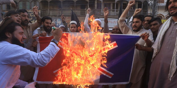 Männer posieren mit brennender französischer Flagge