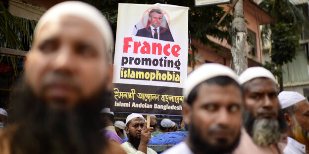 Mehrere Muslime halten auf einer Demonstration Schilder in die Höhe und protestieren gegen Mohammed-Karikaturen