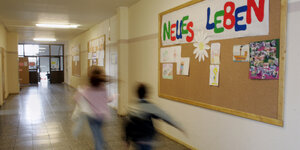 Kinder laufen im Flur eines Kinder- und Jungendzentrums in Berlin, an der Pinnwand steht in großen bunten Buchstaben "Neues Leben"