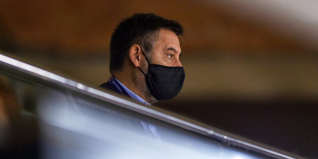 Ein Mann mit Mund-Nasenbedeckung sitzt alleine auf der Tribüne des Stadions des FC Barcelona