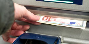 Ein Bankautomat gibt mehrere Euroscheine aus.