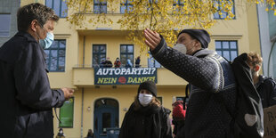 Demonstrantinnen und Demonstranten diskutieren mit Robert Habeck vorm Grünenbüro - einem gelben Gebaeude an dem Transparente hängen.