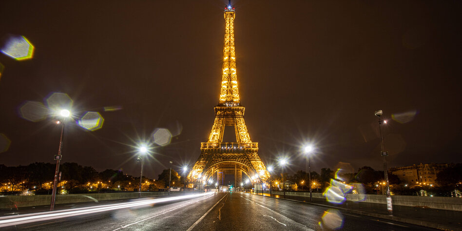 Der Eiffelturm im Dunkeln, davor eine komplett menschenleere Straße
