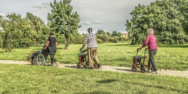 Rentner aus einem Altersheim im Rollstuhl und mit Rollator beim Spaziergang durch eine Parklandschaft