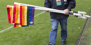 Mann trägt Regenbogenfahne vom Fußballfeld