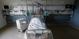 Ein Krankenhausbett auf einer Intensivstation ist mit einer Plastikplane verdeckt