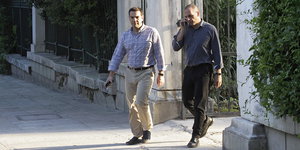 Tsipras und Varoufakis laufen durch ein Steintor