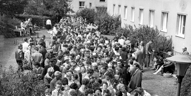 Menschen stehen vorm Aufnahmelager in Berlin-Marienfeld Schlange