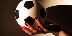 Ein Minifußball in einer Frauenhand