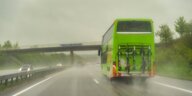 Ein grüner Flixbus fährt auf regennasser Autobahn