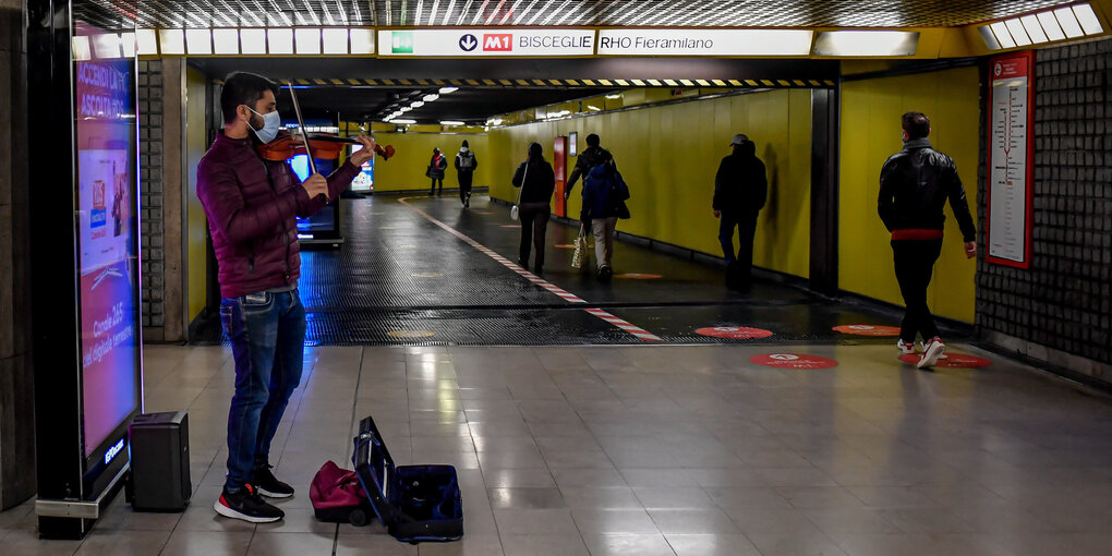 Eine Straßenmusiker mit Geige steht in einer U-Bahn-Station in Mailand