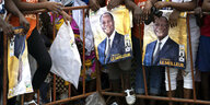 Menschen halten Plakate mit Dem Portrait des ivoirianischen Präsidenten Ouattara