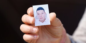 Eine Hand hält eine Passfoto des Attentäters von Nizza