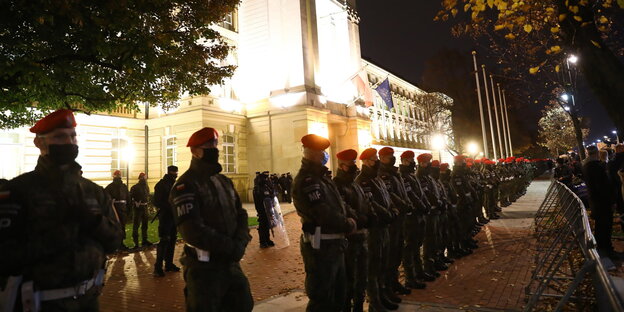 Polizisten mit Schilden stehen vor einem angeleuchteten Gebäude