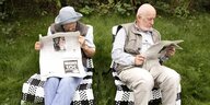 Ein Seniorenpaar liest Zeitung im Garten.