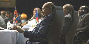Sudans Präsident Omar al-Bashir sitzt an einem Tisch, umgeben von seinen Kollegen.