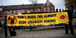 Nordenham: Demonstranten halten ein Protestplakat mit der Aufschrift "don't nuke the climate, stop uranium mining" (etwa: Atomisiert nicht das Klima, beendet den Uranium-Bergbau). Sechs Castor-Behälter mit hochradioaktivem Atommüll aus der britischen Wied