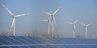Windräere hinter einem Feld mit Solarpanels