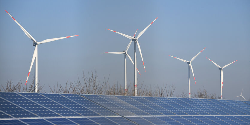 Windräere hinter einem Feld mit Solarpanels