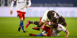 Ein Fußballspieler krabbelt über einen anderen Fußballspieler und irgendwo muss auch der Ball sein.