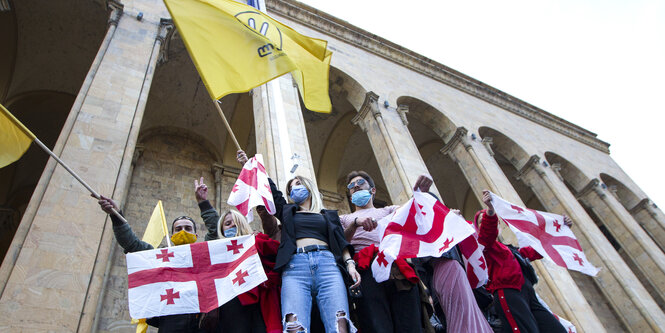 Personen mit Fahnen vor Parlament in Tiflis