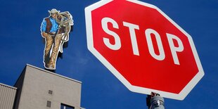 Pappaufsteller auf Gebäude, davor ein Stopschild