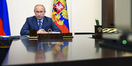 Wladimir Putin sitzt an einem Schreibtisch und nimmt an einer Videokonferenz teil