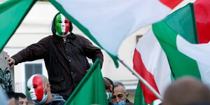 Demonstranten tragen Masken und Flaggen in den Italien- Landesfarben Grün, Rot, Weiß