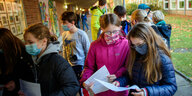 Kinder stehen auf einem Schulhof und schauen auf Arbeitsblätter