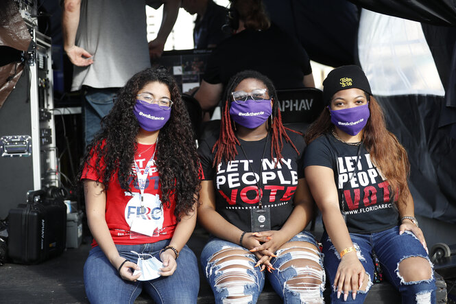 Drei junge schwarze Frauen mit Gesichtsmaske und T-Shirts mit dem Slogan "Let my people vote"