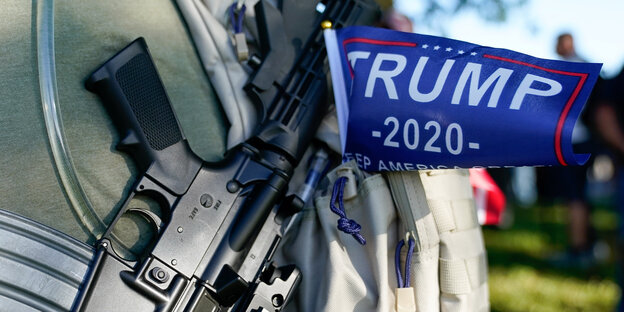 Ein Fähnchen mit der Aufschrift Trump 2020 hängt an einem Sturmgewehr eines militanten Trumop-Anhängers