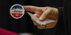 USA, New York: Ein Wahlhelfer bereitet sich im Madison Square Garden am Tag der US-Präsidentschaftswahl darauf vor einem Wähler den Aufkleber "I Voted" (Ich habe gewählt) zu geben.