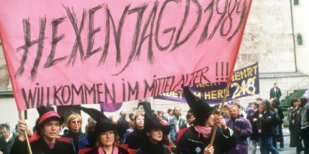 Frauen in Hexenkostümen tragen ein Transparent mit der Aufschrift "Hexenjagd"