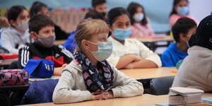 Kinder mit Mundschutzmasken folgen dem Unterricht