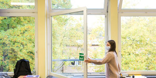 Schülerin öffnet ein Fenster in einem Klassenraum