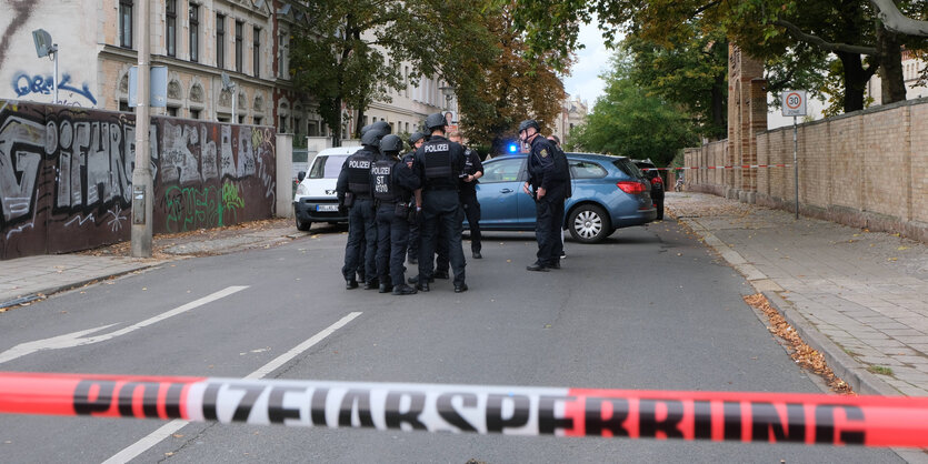 Eine Gruppe Politisten steht hinter dem Absperrband vo der Jüdischan Synagoge in Halle an der Saale