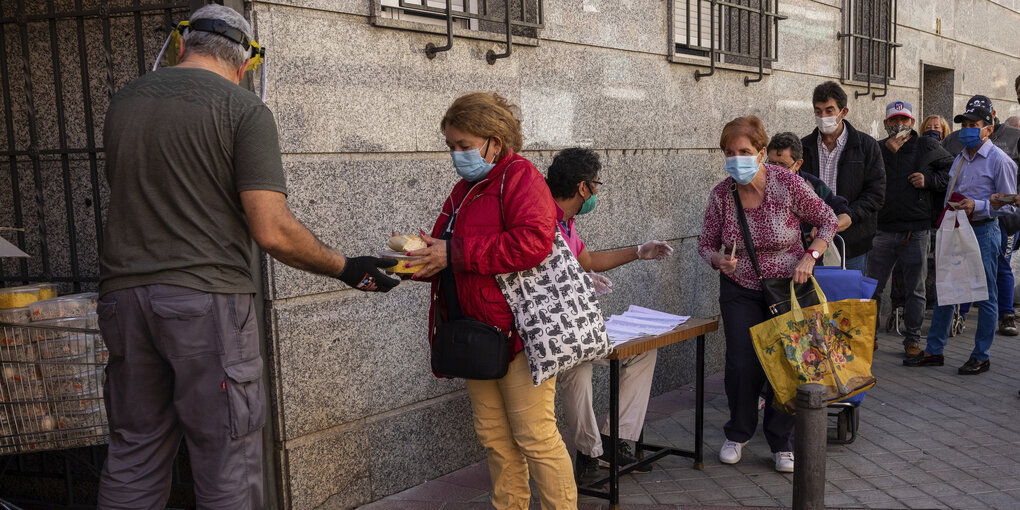 Menschen warten vor einem katholischen Orden in Madrid, wo Freiwillige Lebensmittel verteilen